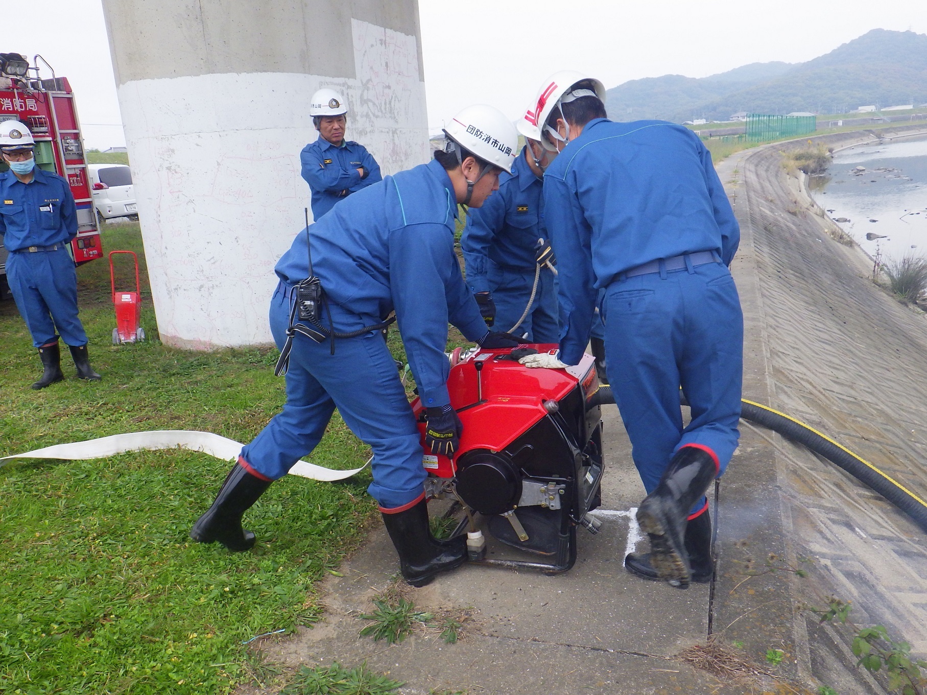 消防団員が可搬ポンプを始動しています。