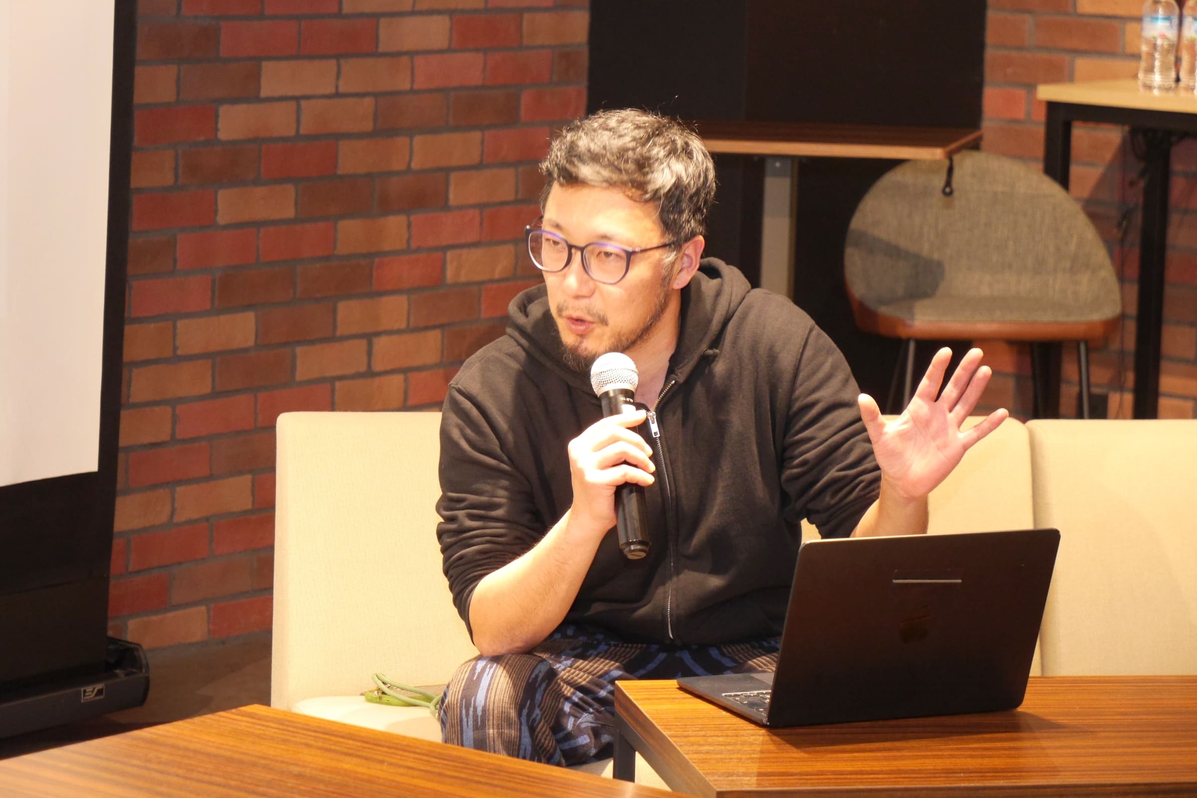 マイクを持って座っている大熊 充氏の写真