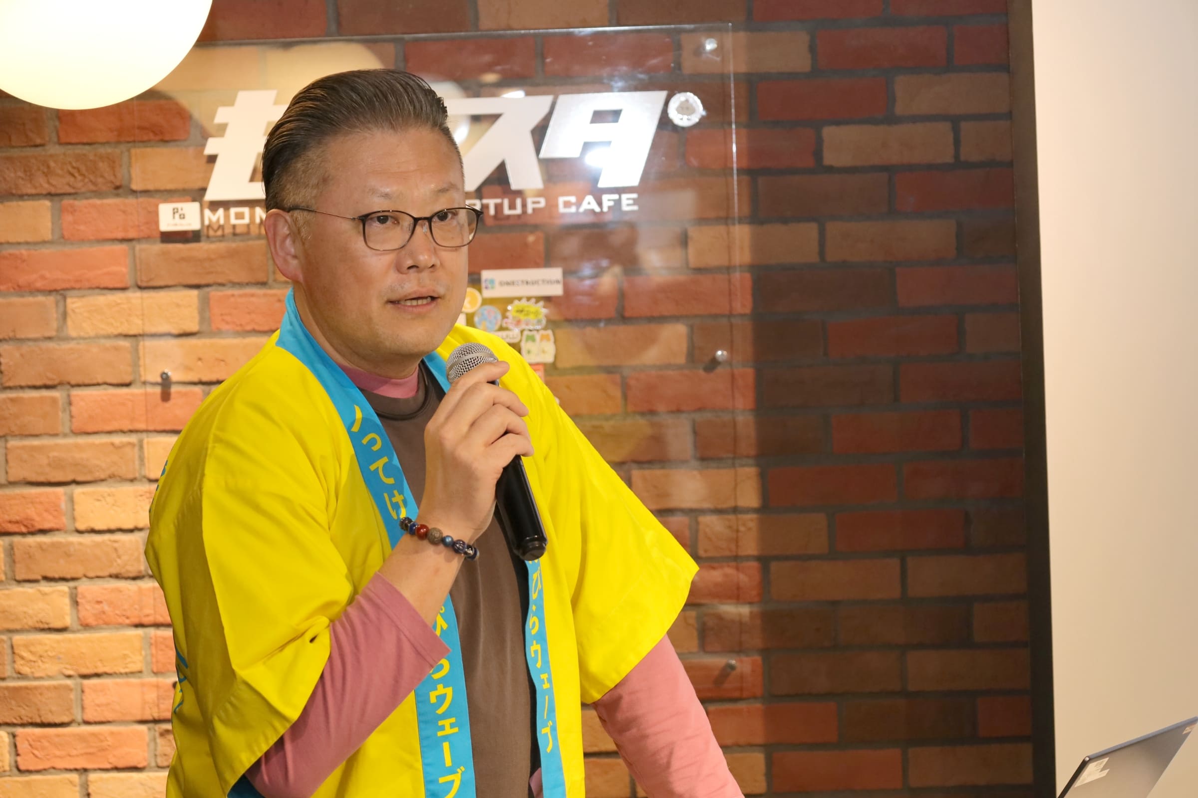 マイクを持ってしゃべっている近江淳氏の写真