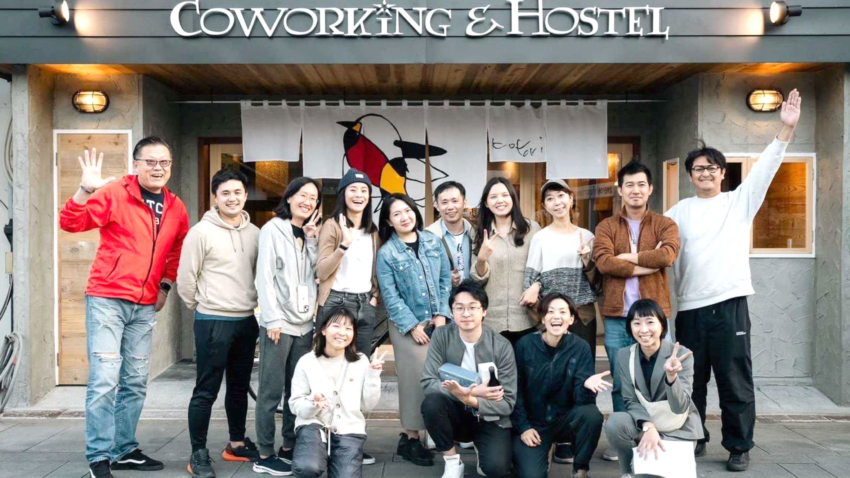 コワーキング&ホステルの前で大勢の人が記念写真を撮っている様子