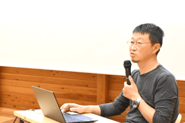実際の講演でマイクをもって話す牧氏の様子