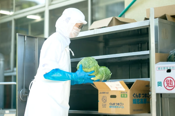 キャベツを運ぶ給食調理員の写真