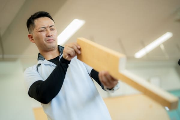 木を持っている用務員の写真